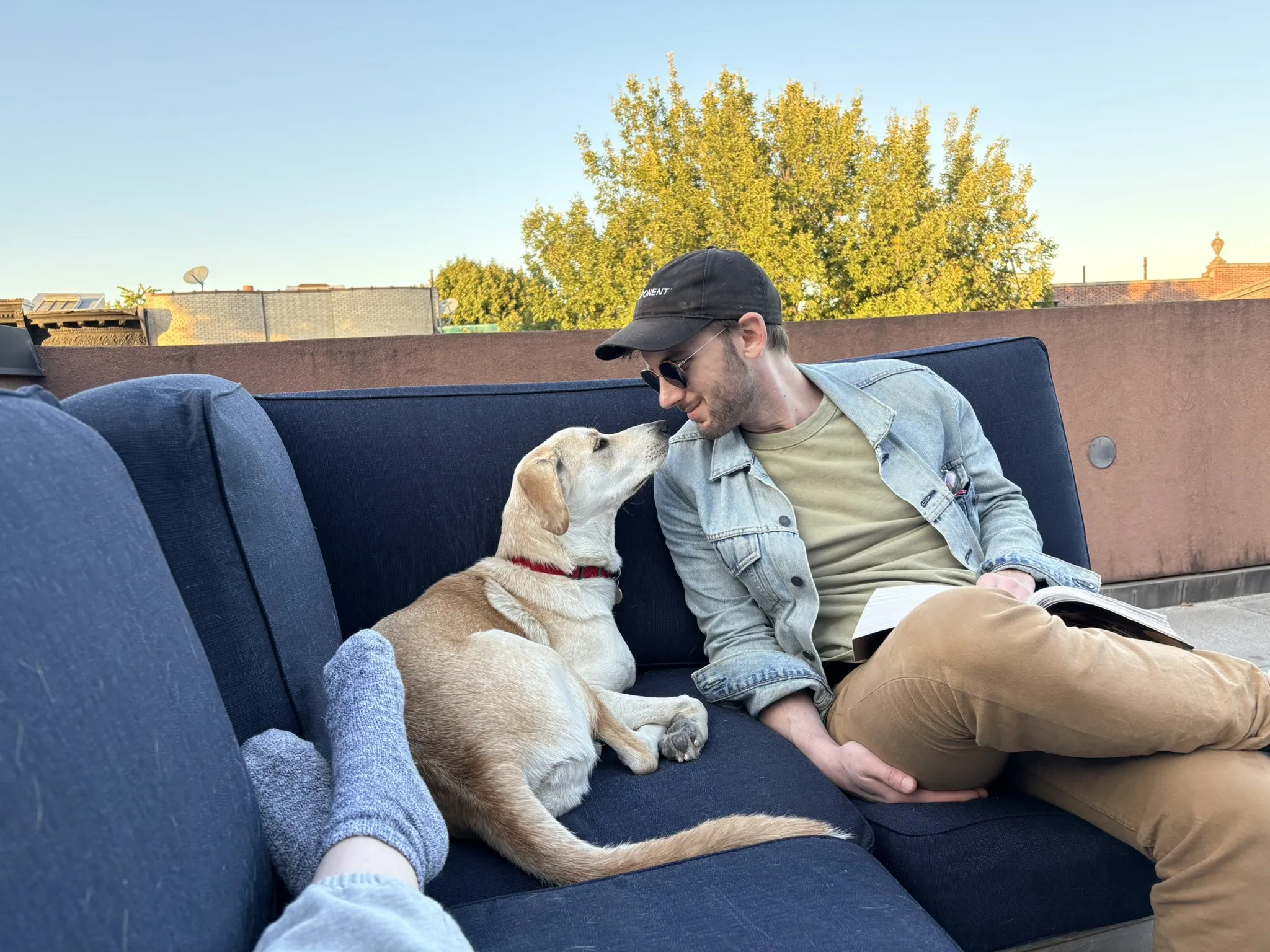 Gabby and me sitting outside on a couch on a beautiful sunny summer day. Our noses are touching and I'm smiling. Gabby is a yellow dog that weighs about 45 pounds.